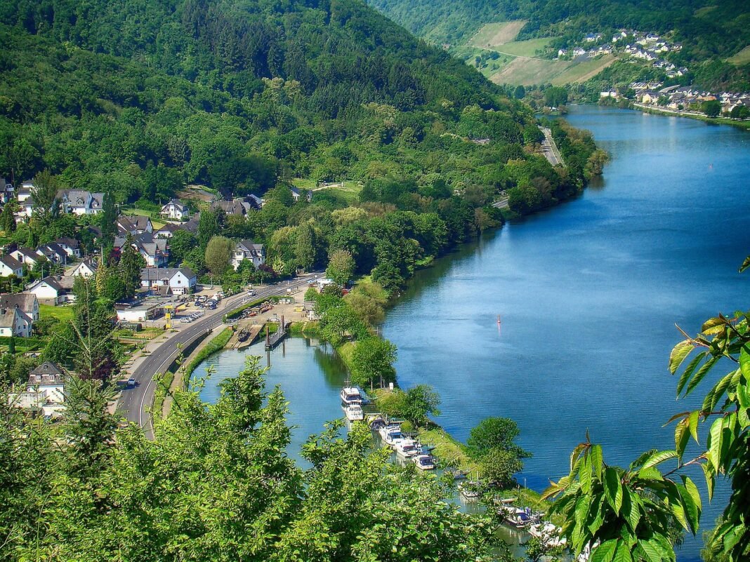 Paisagem da região de Mosel, na Alemanha, com o rio sinuoso entre montanhas verdes e vinhedos nas encostas.