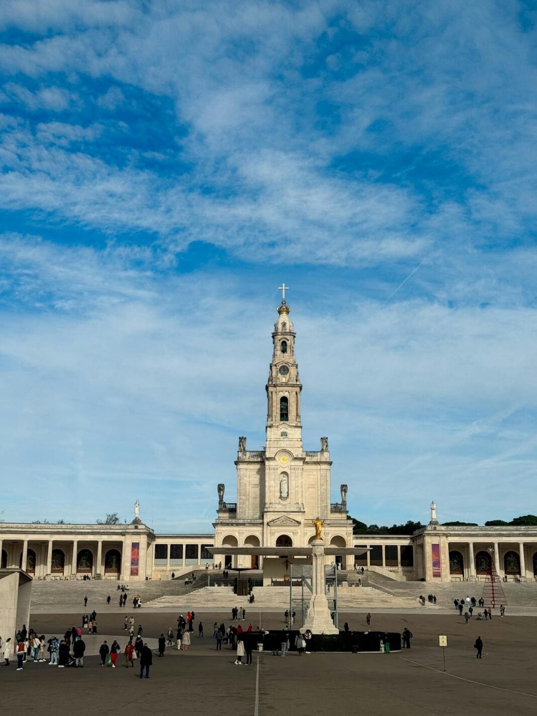 Basílica de Nossa Senhora do Rosário de Fátima com sua torre imponente e fachada branca sob céu azul claro.