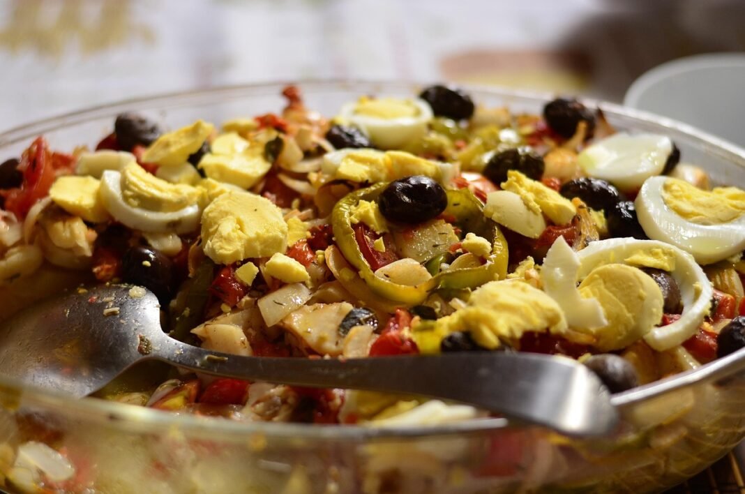 Prato tradicional português com bacalhau assado, batatas douradas, cebolas caramelizadas, azeitonas pretas e salsa fresca por cima.