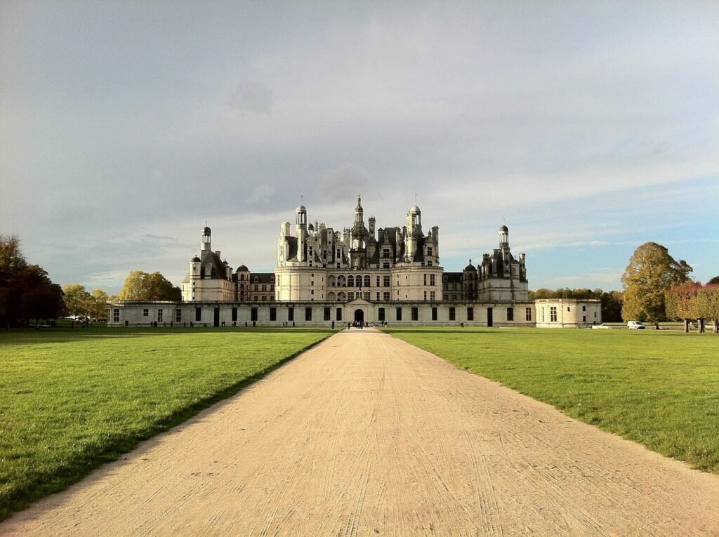 Castelo estilo Châteaux na França com torres elegantes, arquitetura clássica e jardins bem cuidados ao redor.
