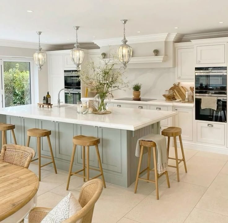Cozinha moderna com ilha central branca, armários azul claro e banquetas de madeira, em ambiente iluminado e elegante.