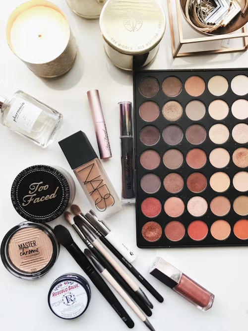 Bancada branca com produtos de maquiagem organizados, incluindo sombras, pincéis, base e batons.