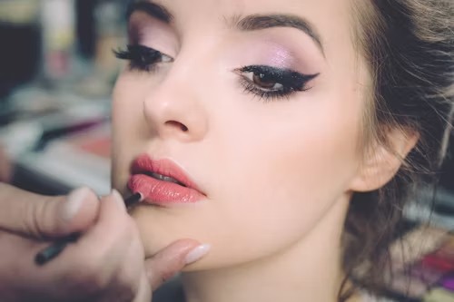 Mulher sendo maquiada com produtos básicos, com foco em uma beleza natural e leve.