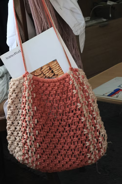 Bolsa de crochê pendurada em uma arara com papéis dentro.