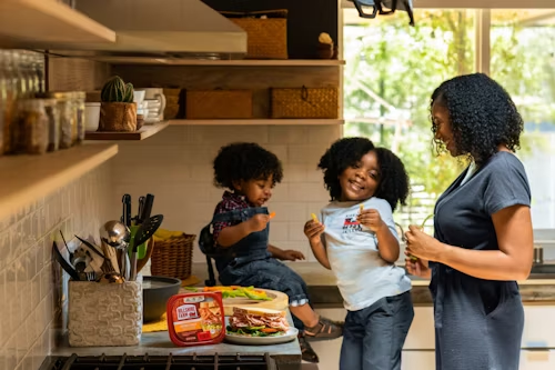 Mãe cozinha com seus filhos sorridentes em uma cozinha moderna e sofisticada.