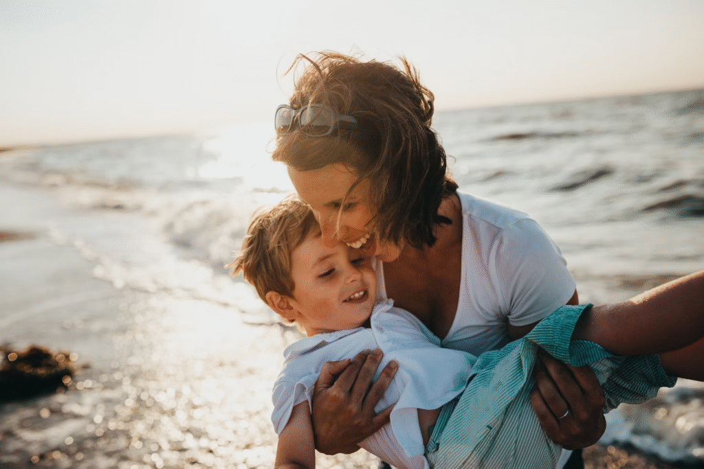 Mãe segura seu filho no colo enquanto brincam juntos na água do mar.