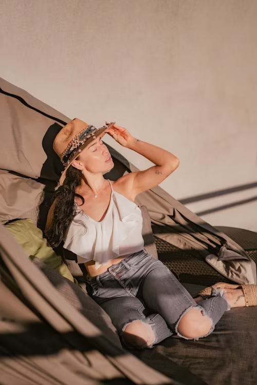Mulher sentada em uma rede aproveitando um momento de descanso sob a luz do sol.