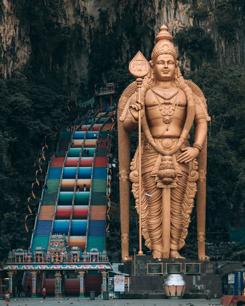 Um dos mais maravilhosos destinos religiosos. Vista do complexo das Batu Caves na Malásia, com a famosa escadaria colorida que leva à entrada da caverna e a imponente estátua dourada de Murugan ao lado.