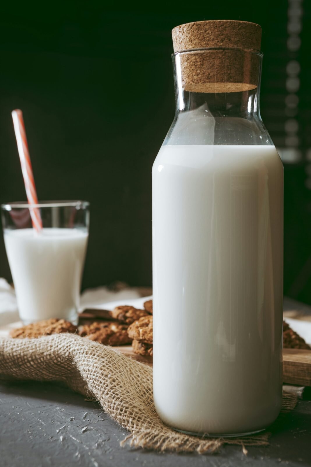 Jarra de leite sobre toalha rústica ao lado de biscoitos, representando o desafio da intolerância à lactose na alimentação cotidiana.