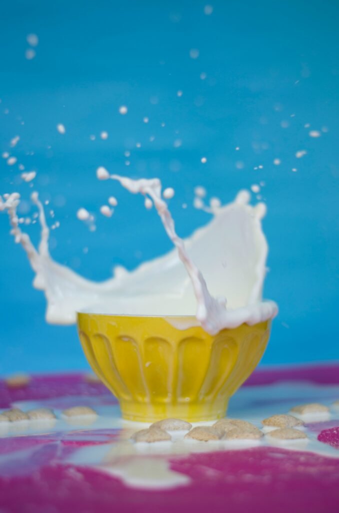 Taça de sobremesa amarela com leite espirrando para fora, simbolizando os efeitos da intolerância à lactose.