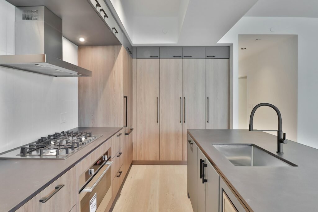 Cozinha moderna com decoração em tons claros, coifa embutida com acabamento em inox e design clean e funcional.
